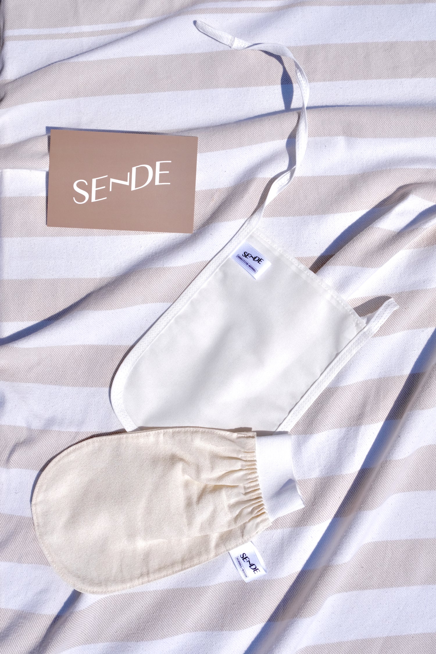 SENDE authentic Turkish body exfoliating keses and thank you post card atop their signature organic sand beige striped peshtemal towel