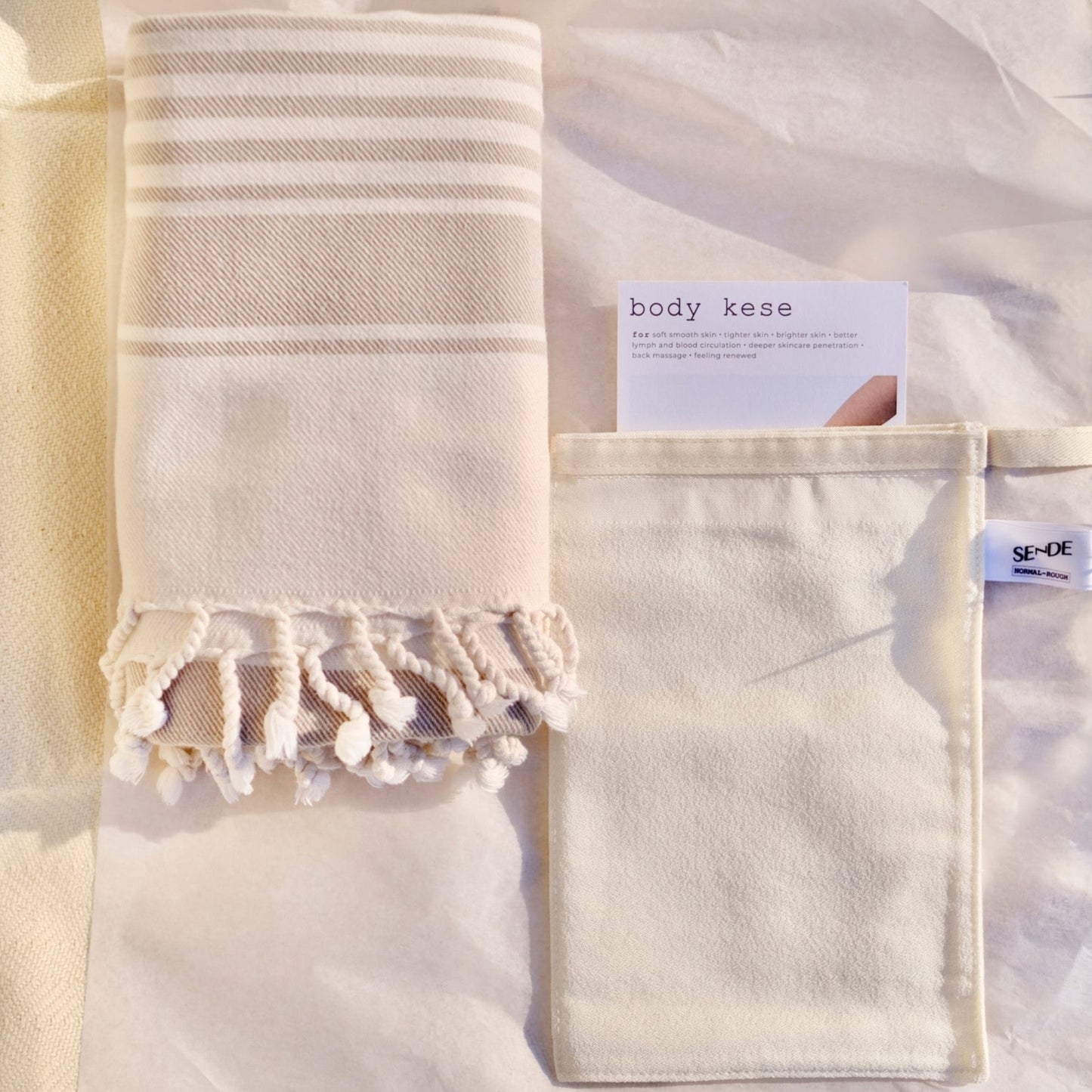 SENDE Turkish towel and exfoliating mitt by SENDE for an At-home hammam Turkish spa bath experience. Flat lay showing SENDE pestemal and body exfoliating kese with instruction card.