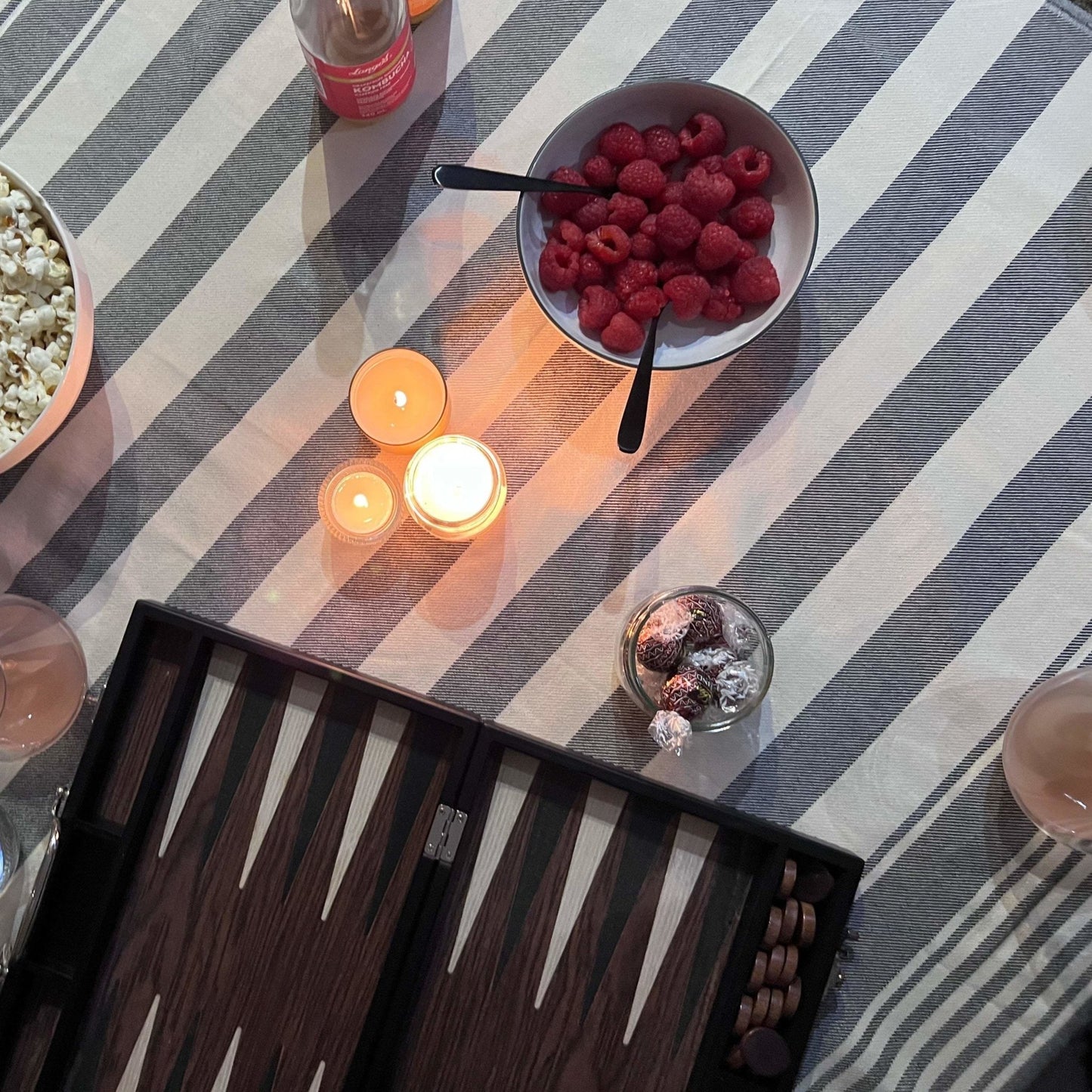 Candle lit raspberry snacks and board games on a striped Turkish towel covered code table | SENDE